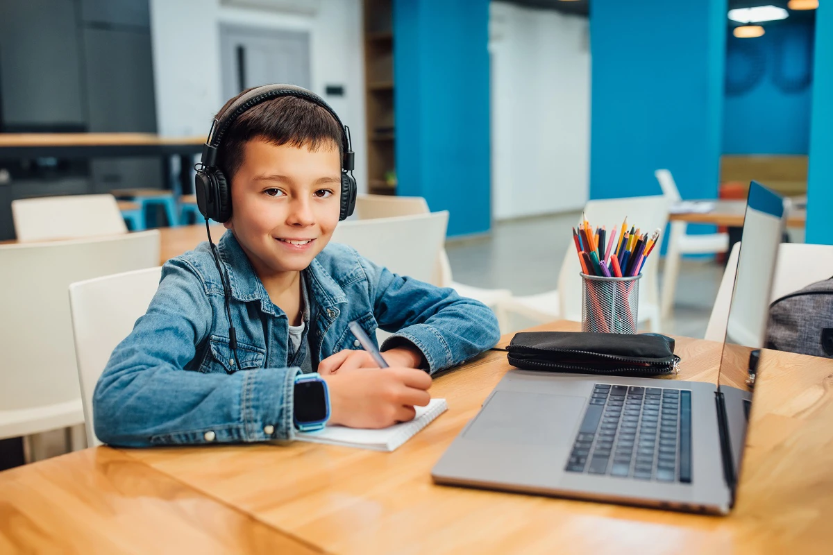 a young kid sitting in classroom working on a computer