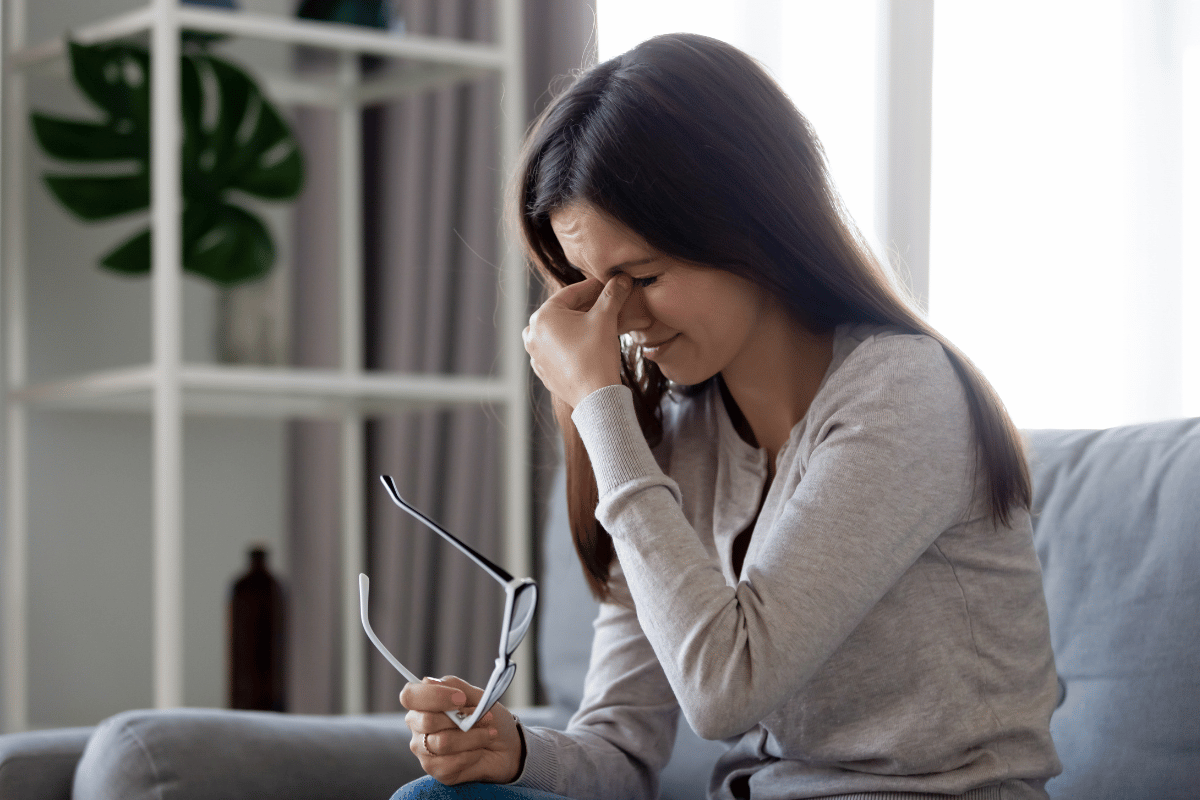a woman taking off her glasses and looking uncomfortable due to dry eyes