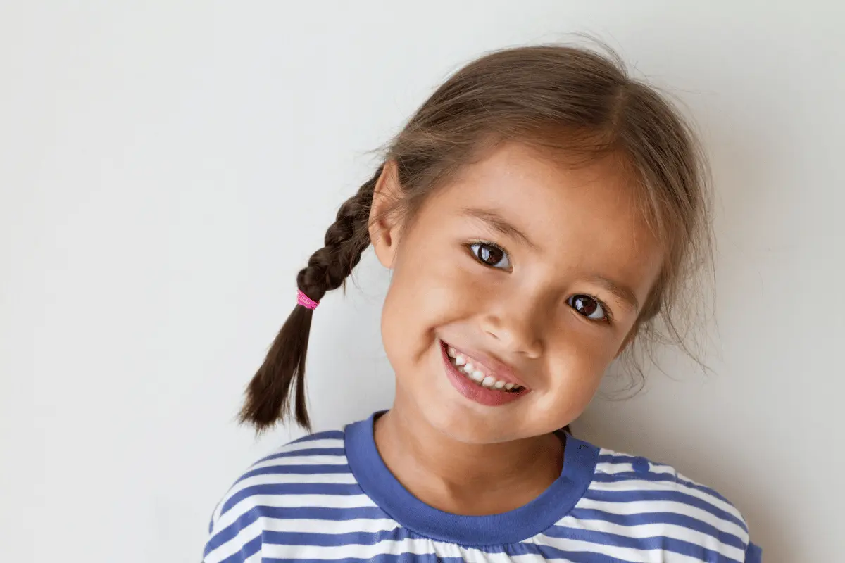 a little girl smiling against a solid color background