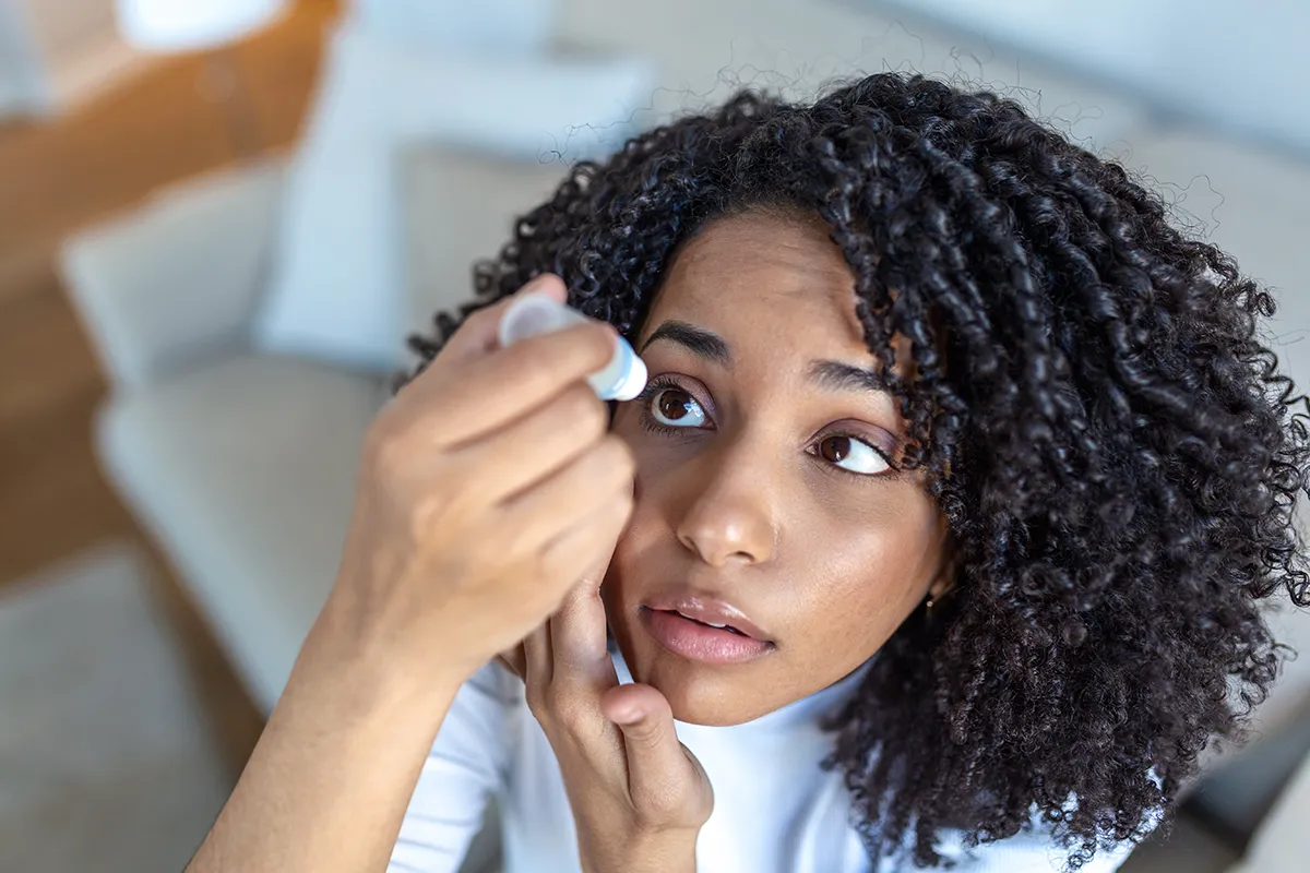 a young woman putting in eye drops for dry eye